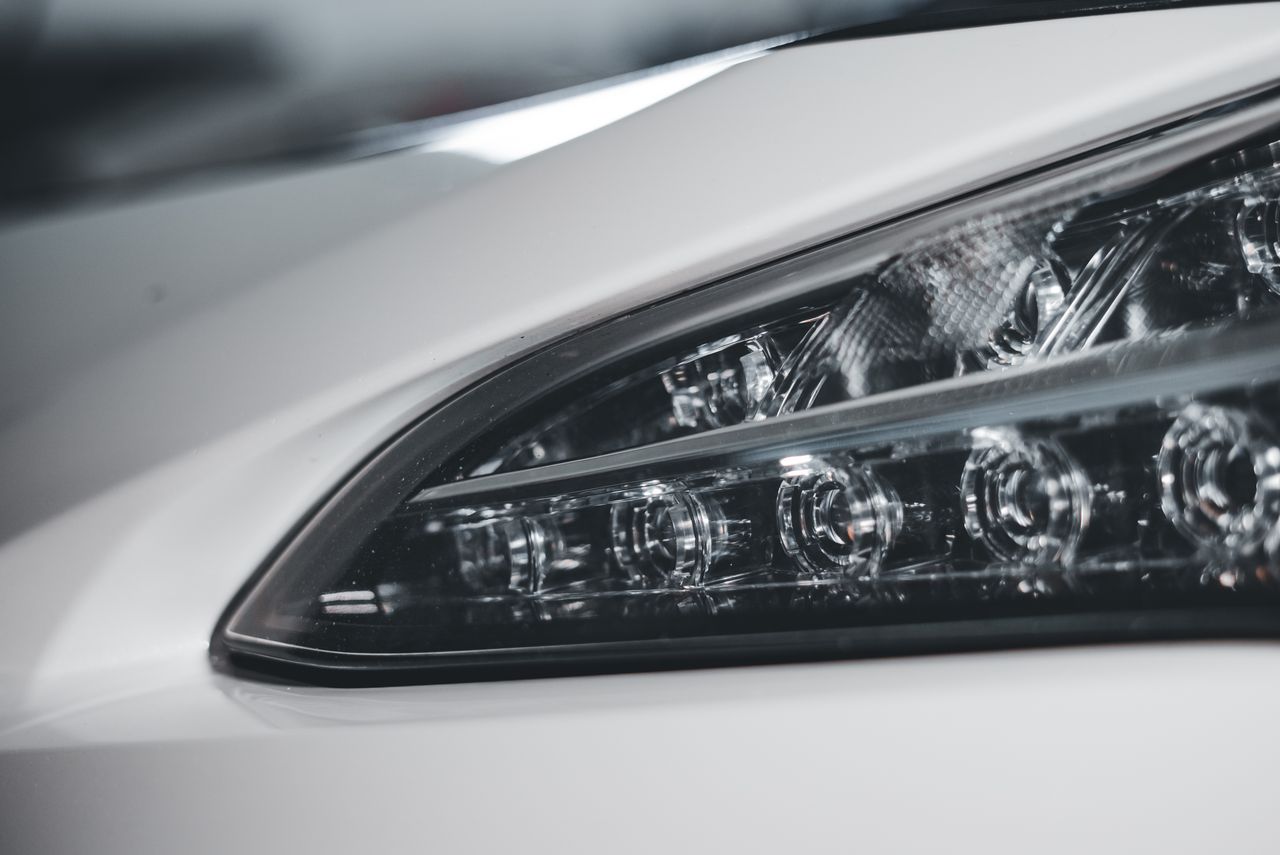 A detailed view of a sleek and modern car headlight on a white vehicle, showcasing design and engineering.