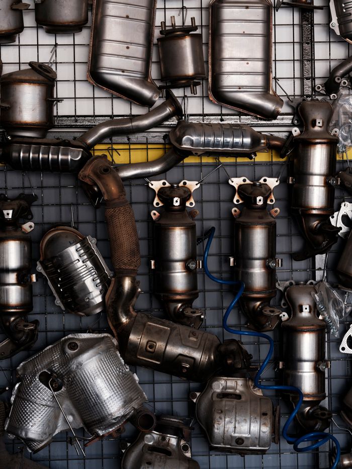 Collection of vintage car exhaust parts hanging in an industrial workshop setting.